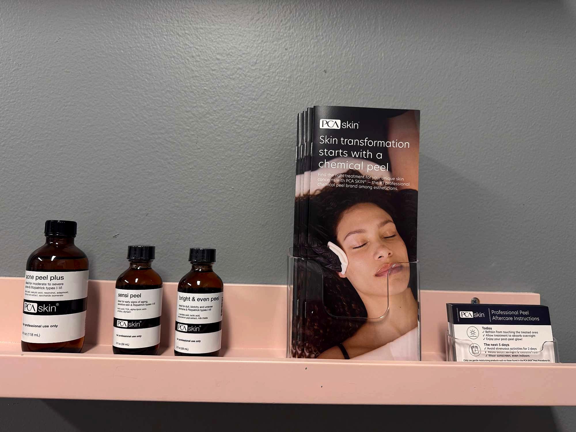 PCA SKIN peel bottles and a brochure on a blush shelf